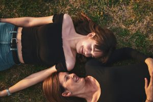 woman in black sleeveless dress lying on green grass field